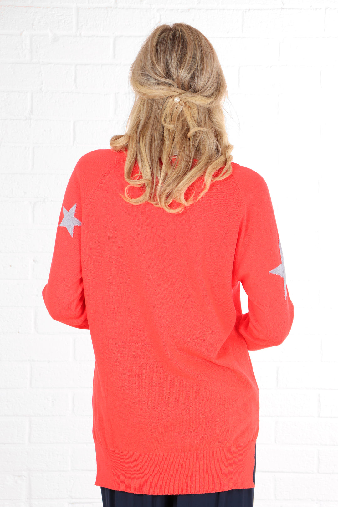 model showing that the back of the cotton jumper is plain coral and has no star pattern on it.