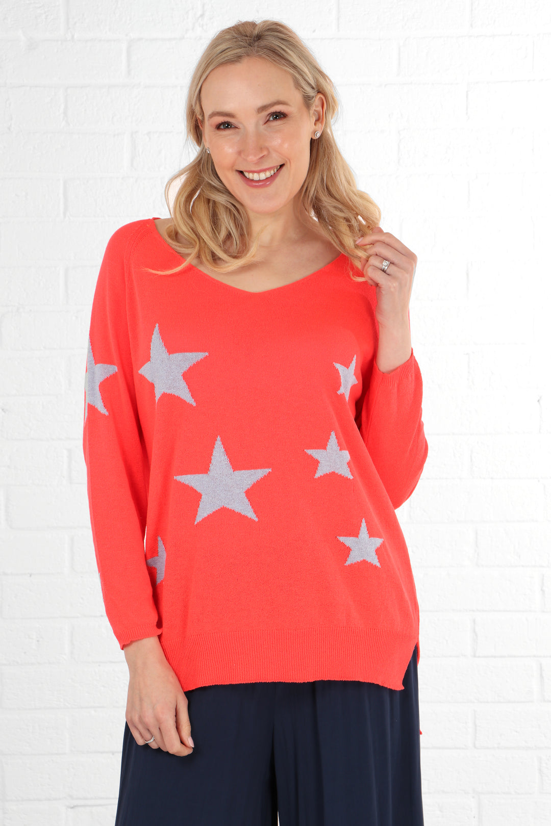 model wearing a coral long sleeve v neck jumper with subtle lilac scattered stars on it