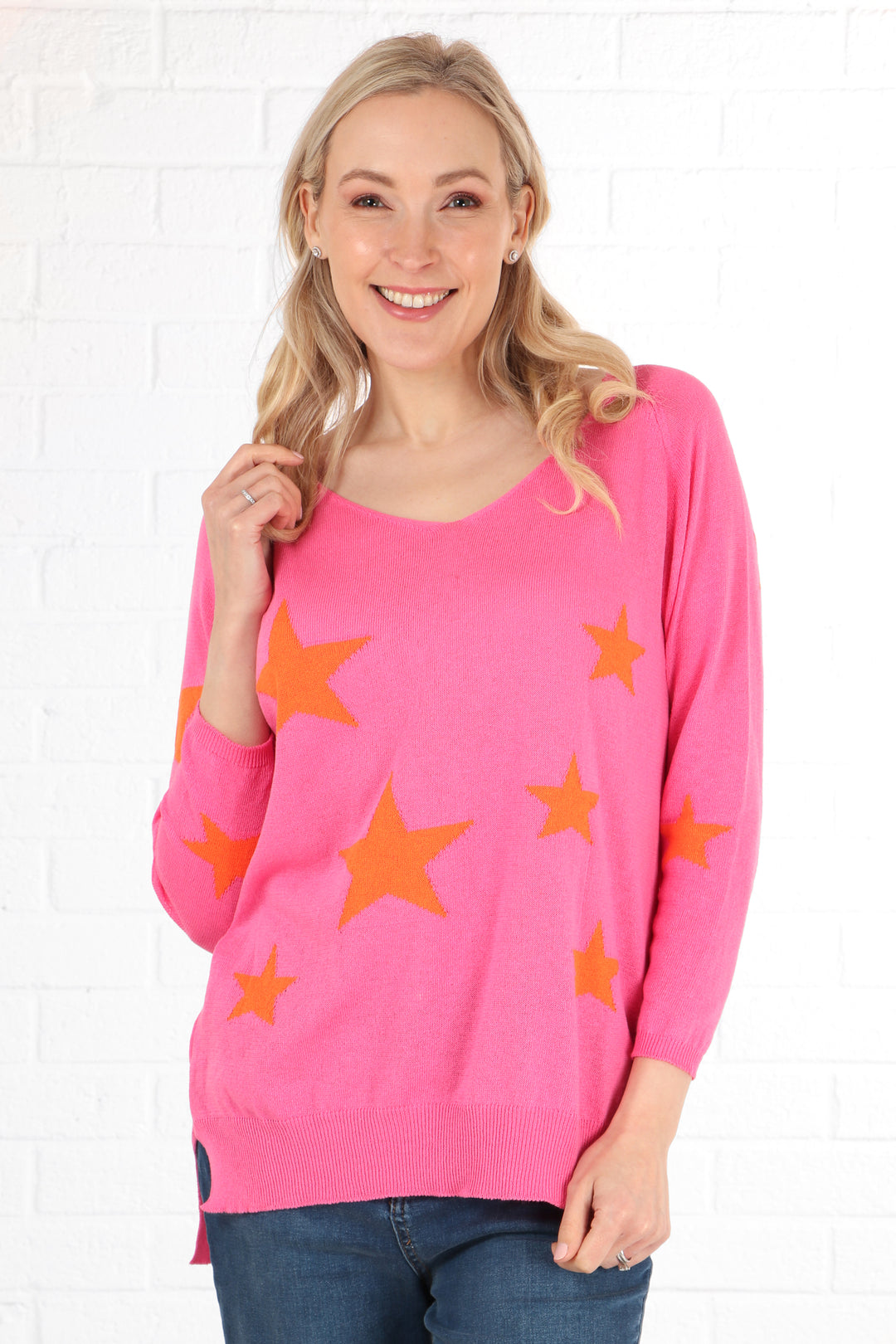 model wearing a pink long sleeve jumper with a scattered orange star print pattern and v neck