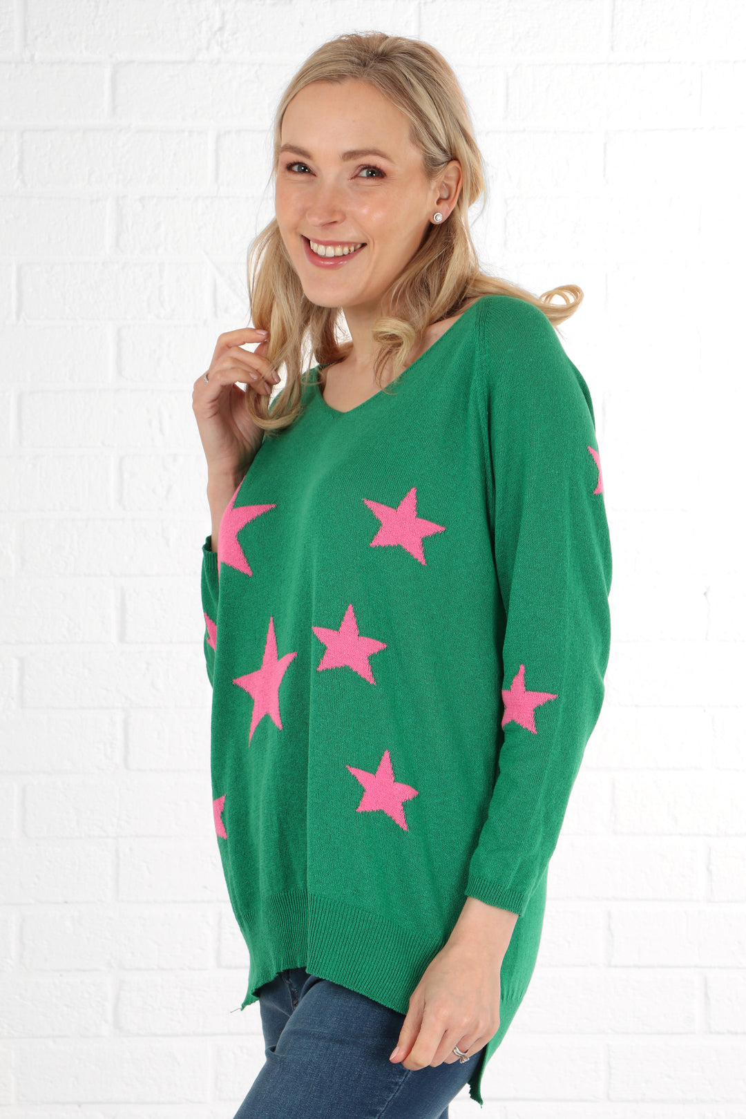 model showing the side of the green star print jumper, showing a dip hem and v-neck