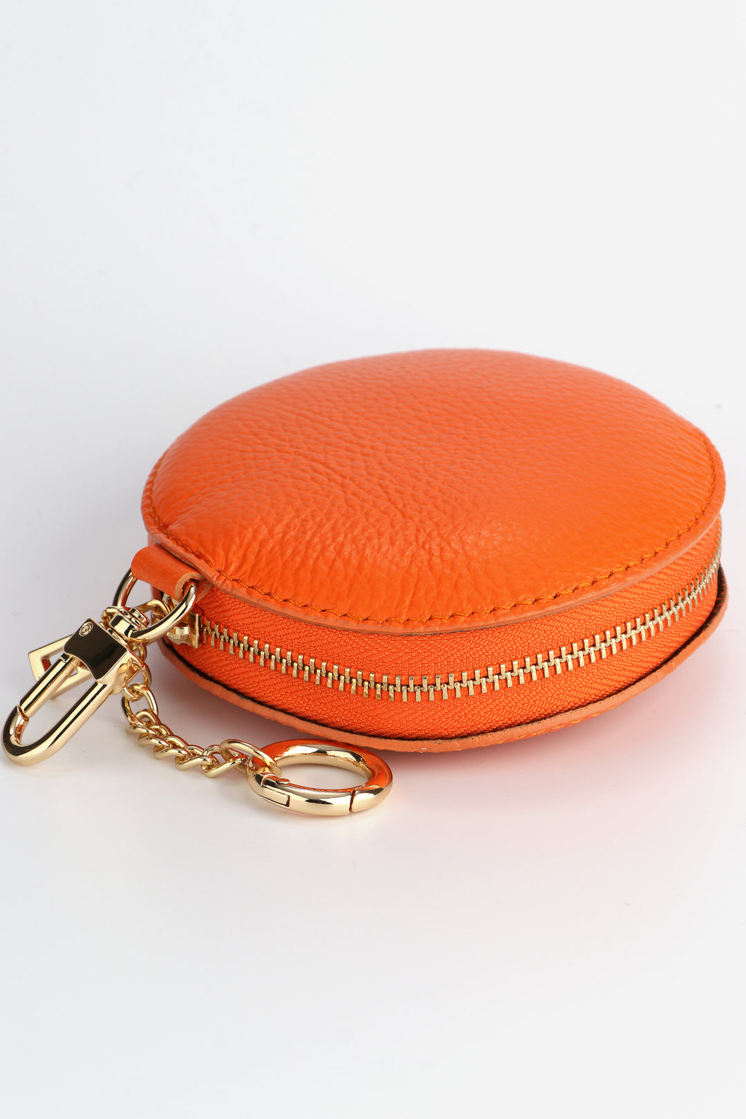 laying flat, showing the secure zip closure of the round orange coin purse