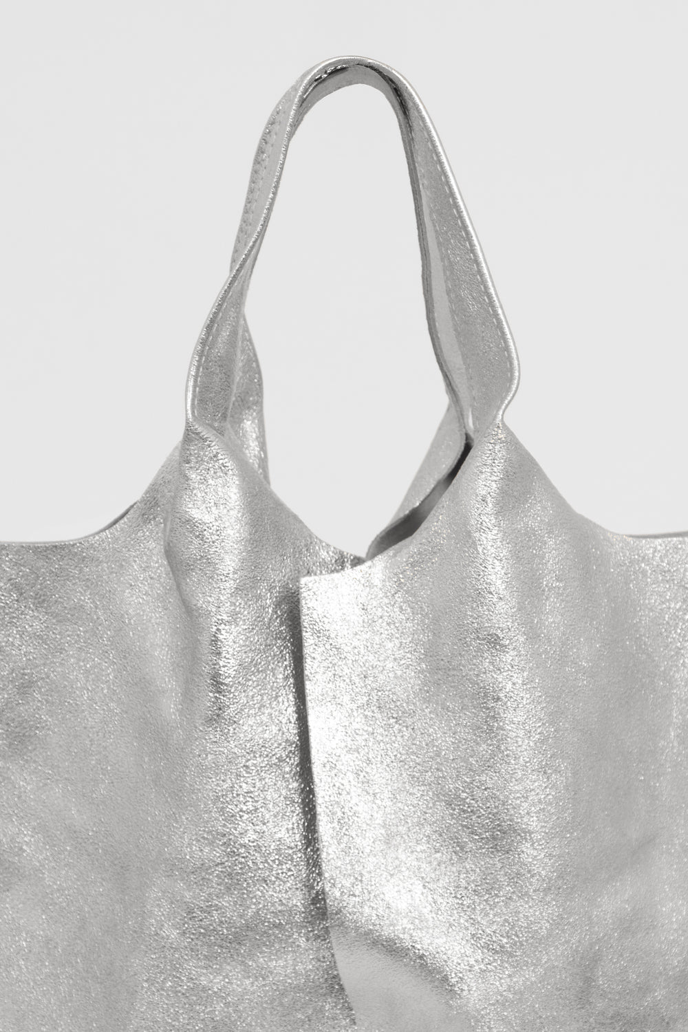 close up of the metallic silver italian leather and the top carry handle on the tote bag.