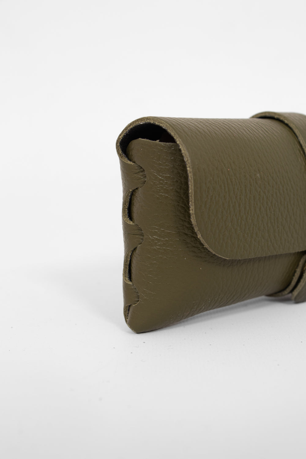 close up of the side view of the sunglasses case, showing the structure of the design. the case has a folding front which is secured by a button fastening