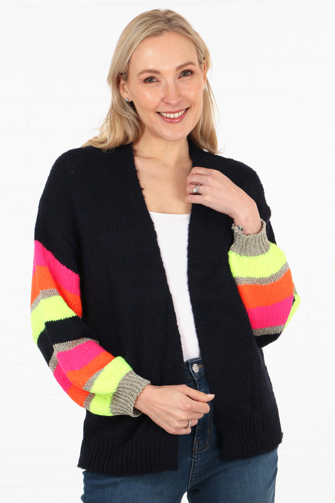 model wearing a navy blue open front cardigan with colourful stiped sleeves. The sleeves are neon yellow, pink, orange and gold glitter striped