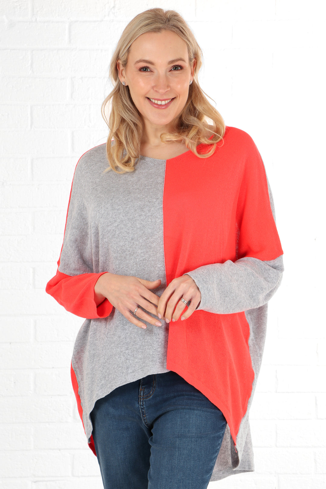 model wearing an oversized batwing cotton jumper in a two tone grey and coral design