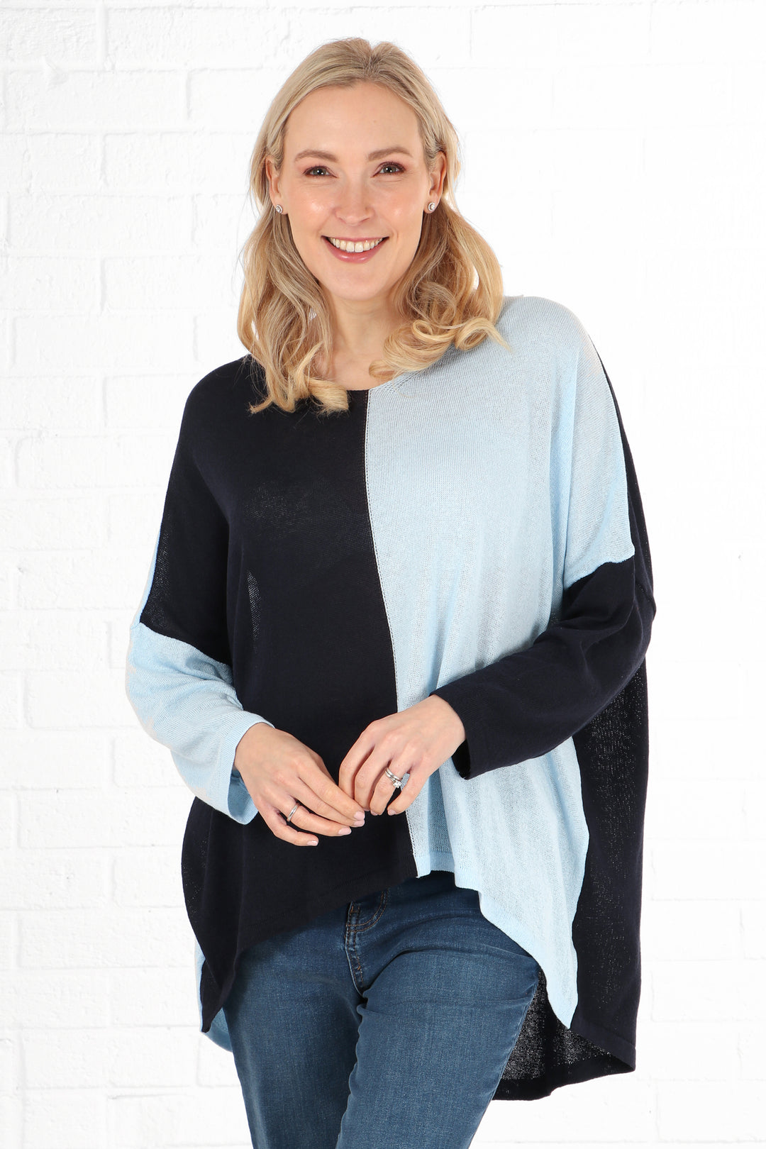 model wearing a navy blue and light blue two tone oversized batwing jumper with long sleeves and a v neck