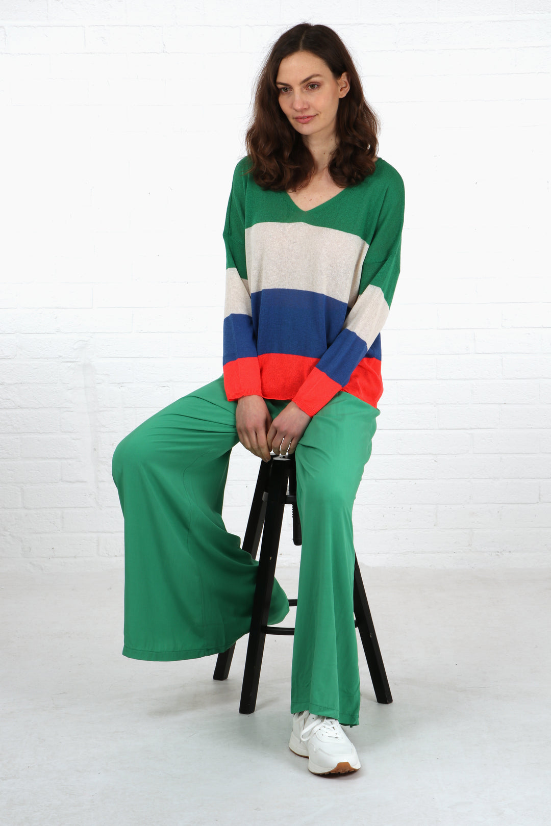 model wearing a pair of plain green wide leg palazzo trousers with a complimentary coluorful striped jumper