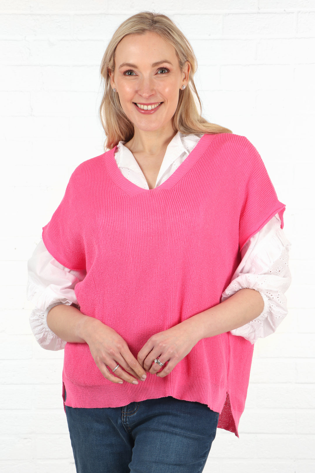 model wearing a pink cotton knitted  v neck sleeveless jumper in fuchsia pink