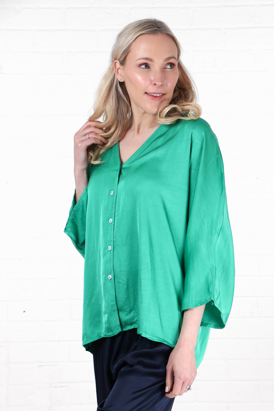 model wearing a loose fitting 3/4 sleeve green silky textured blouse