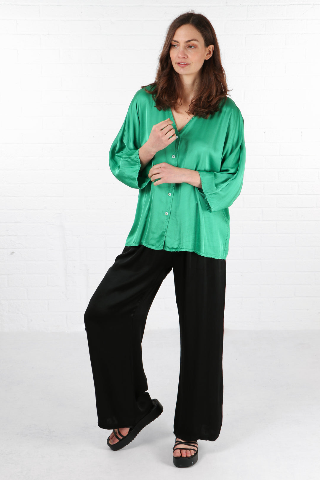 model showing the 3/4 length loose fitting sleeves of the green silky shirt