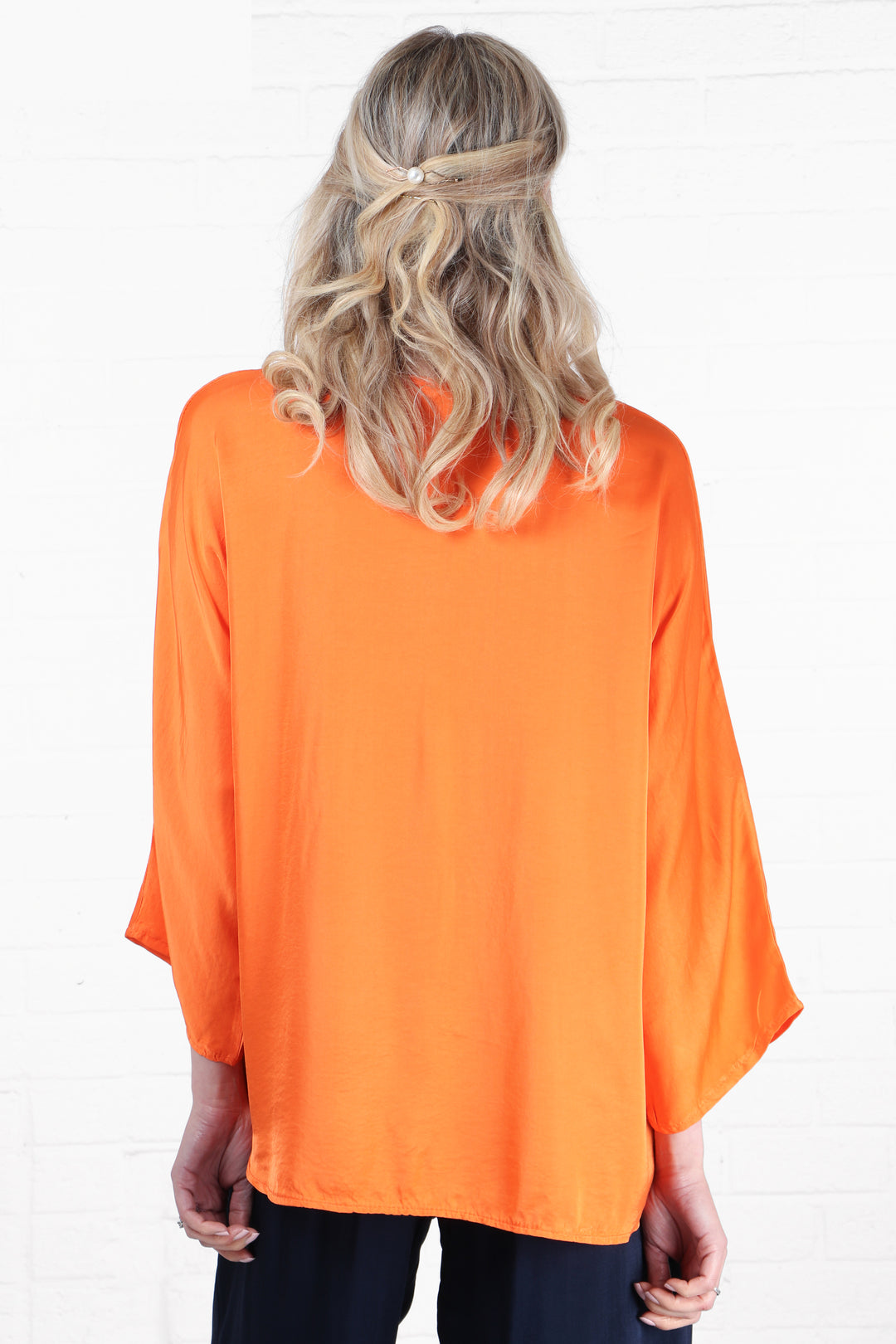 model showing the back of the blouse, showing an all over solid orange colour to the blouse