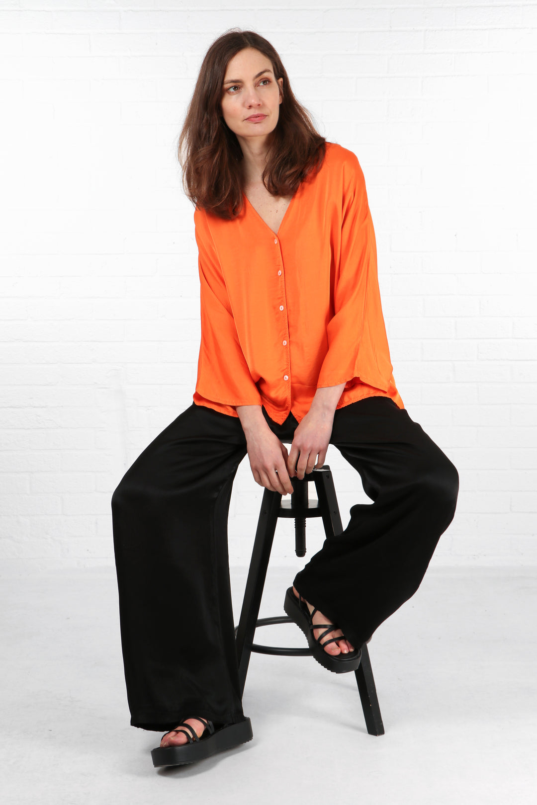model wearing a faux silk 3/4 sleeve orange button front summer blouse