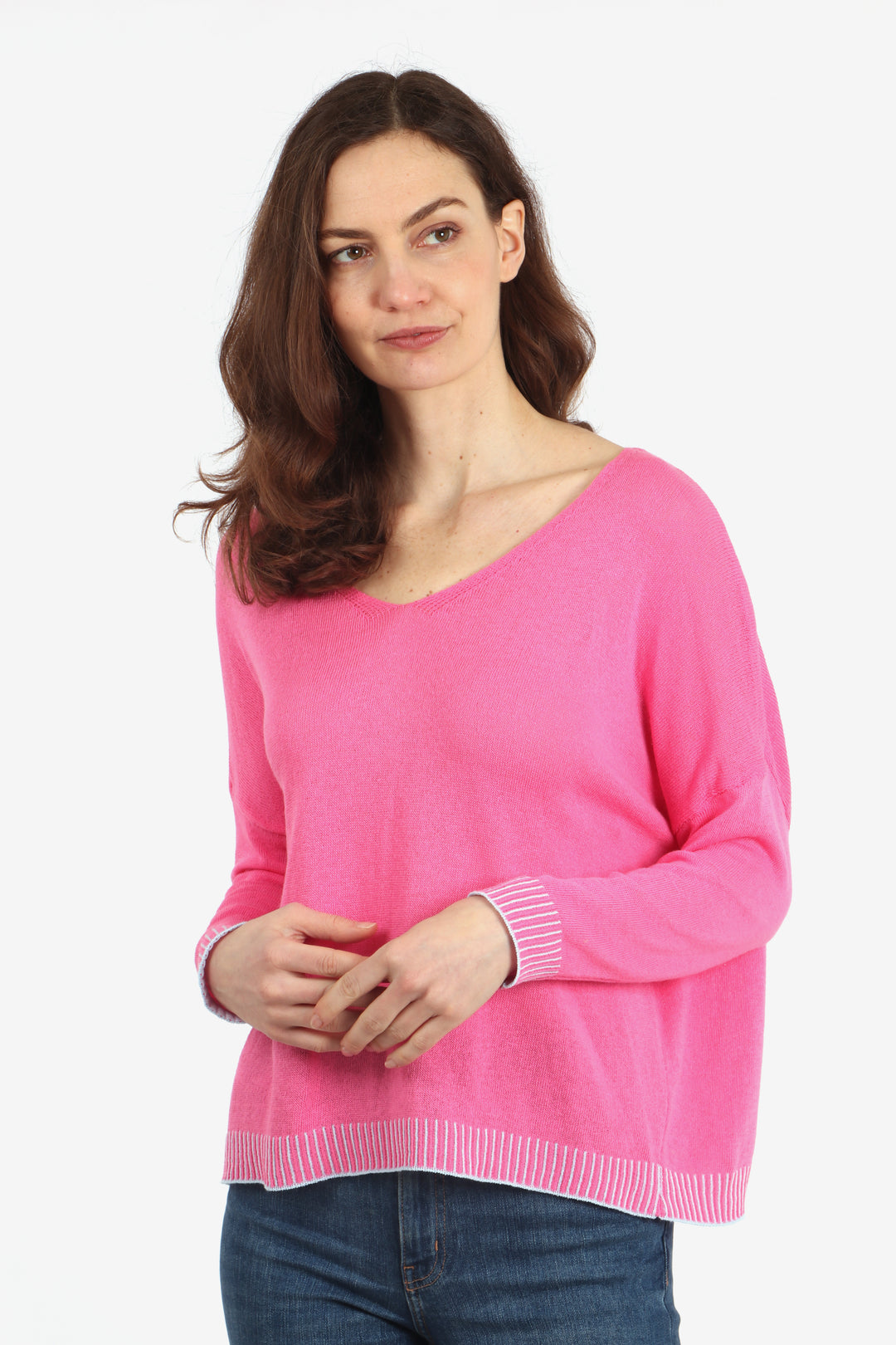 model wearing a pink v neck knitted cotton jumper with contrasting light blue stitching along the bottom edge and cuffs