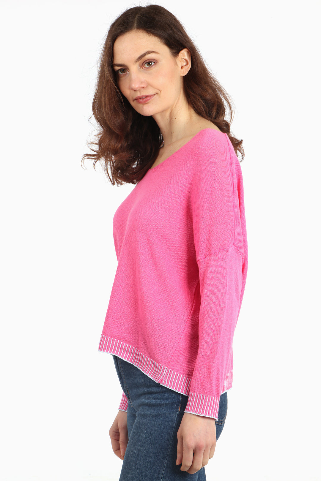model showing a side view of the pink cotton jumper, showing the light blue stitching on the cuffs and edge