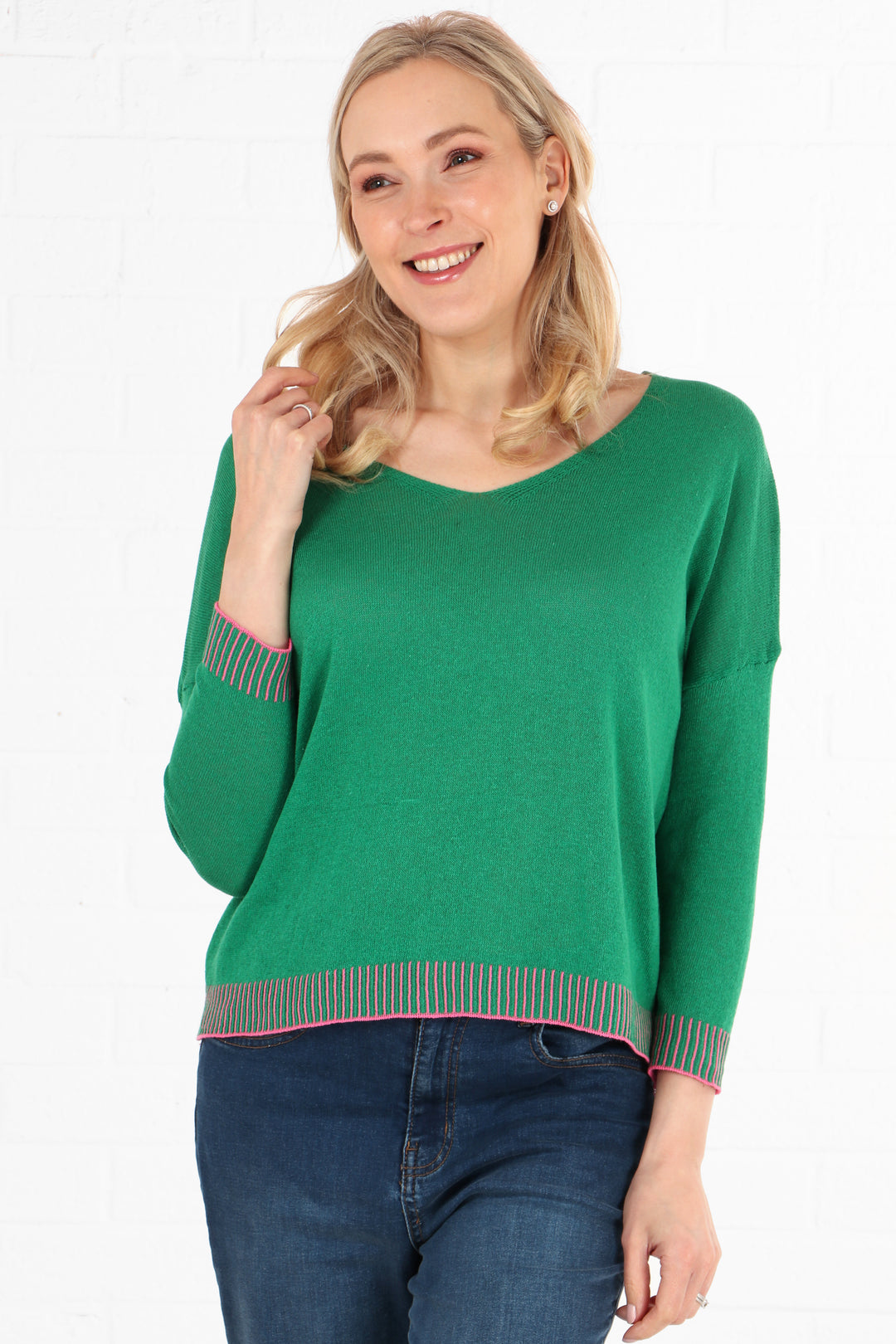 green cotton v-neck jumper with pink stitching along the edge of the cuffs and trim