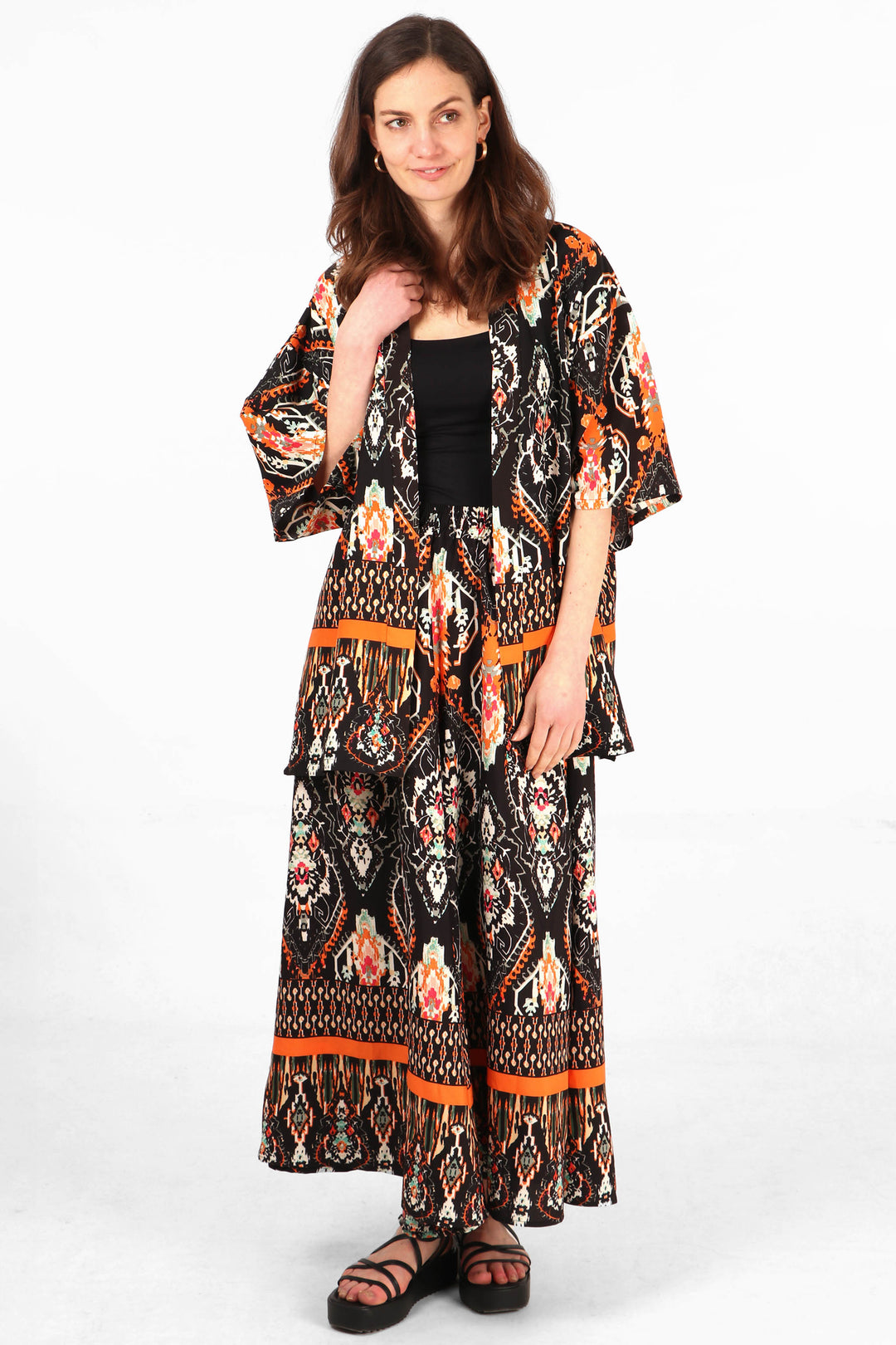 model wearing a black and orange short kimono top with matching palazzo trousers