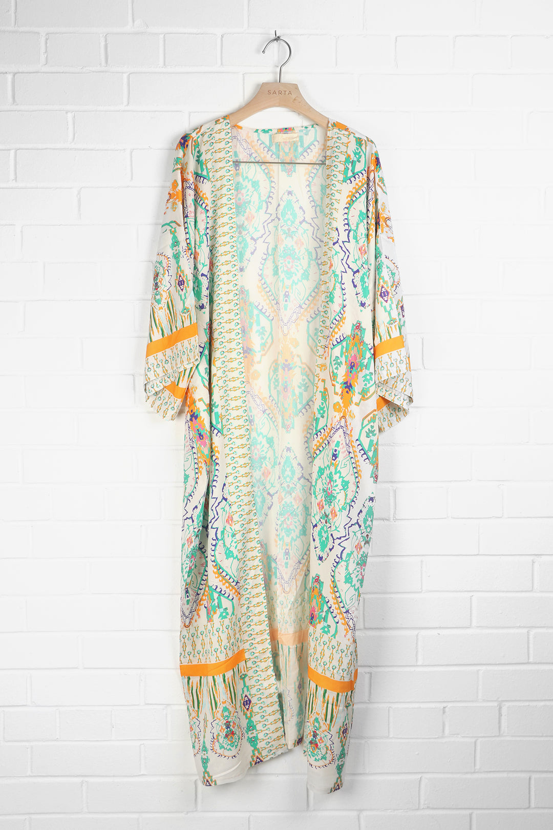 green, cream and orange mandala print kimono draped on a coat hanger