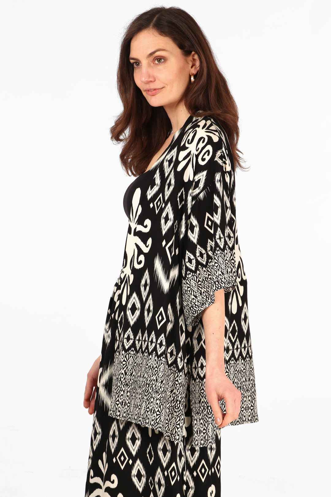 model wearing a black and white ikat pattern short kimono top with 3/4 sleeves and an open front