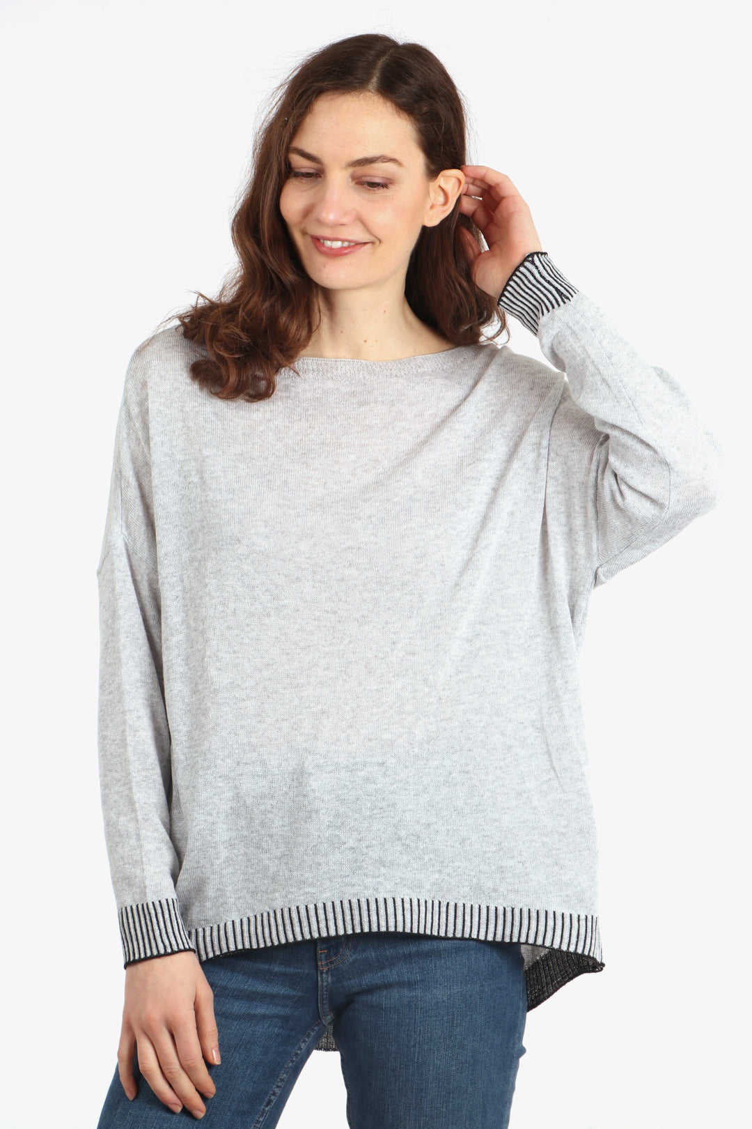 model wearing a long sleeved cotton jumper in light grey with a contrasting black stitched hem and cuff
