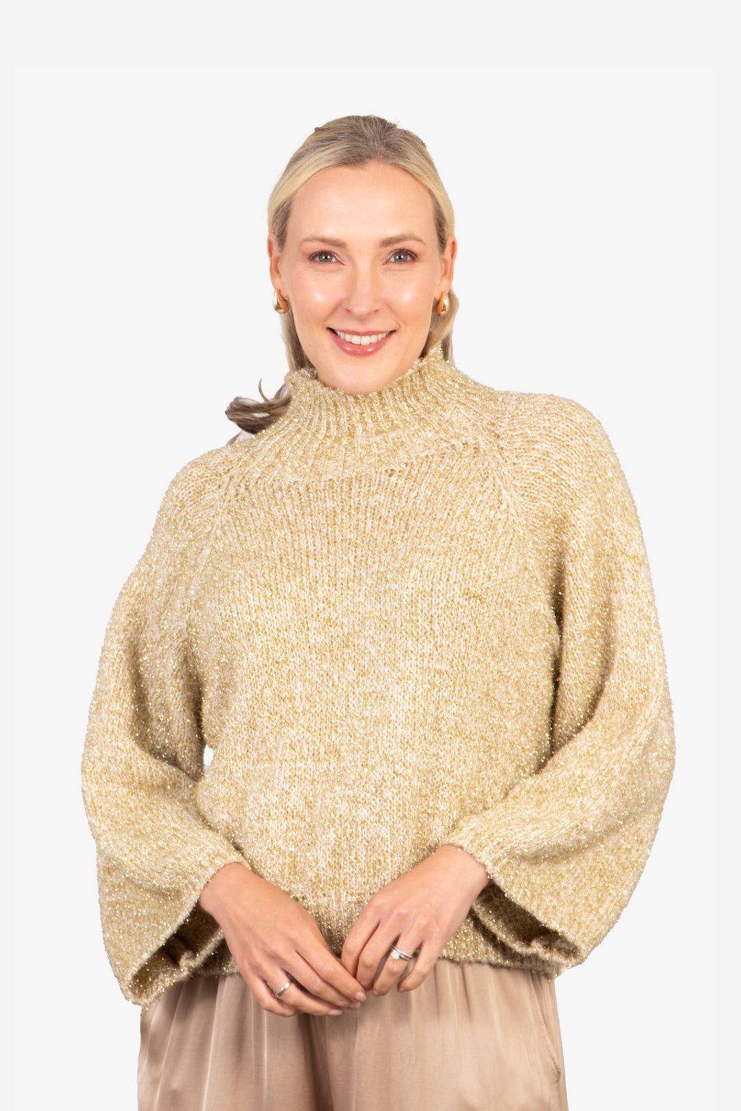 model wearing a gold sparkly knitted jumper, with a knitted high neck and an all over sparkly gold tinsel effect.