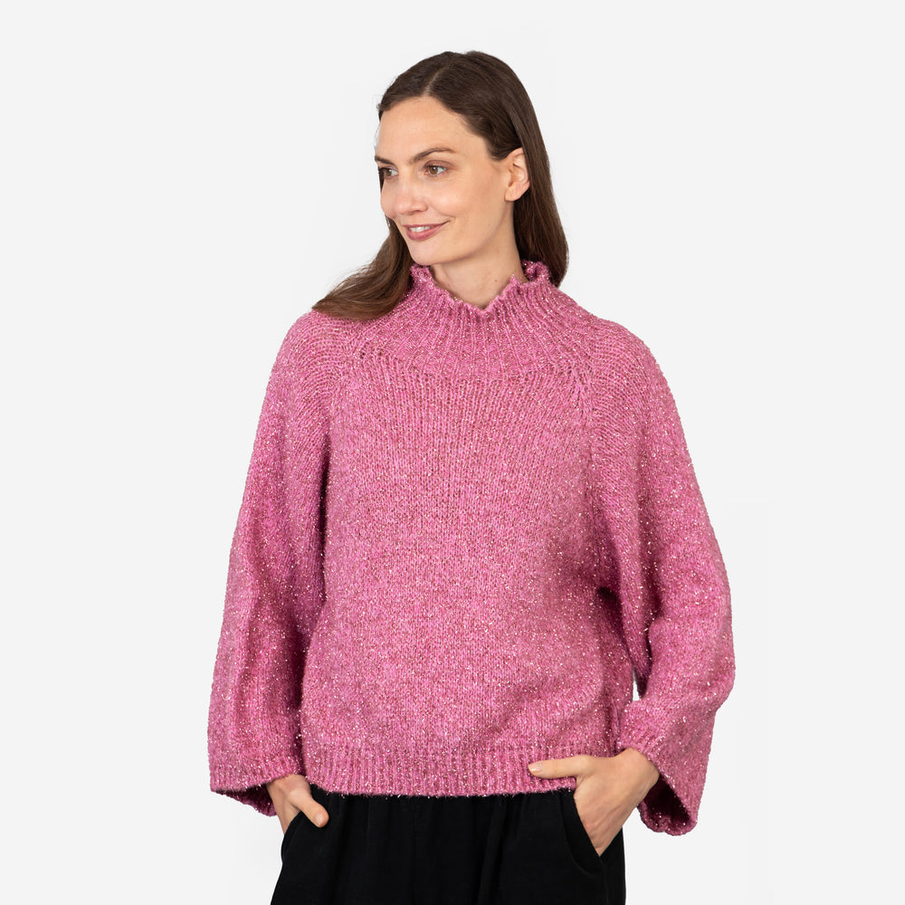 model wearing a sparkly pink jumper, showing the relaxed fitting design of the piece