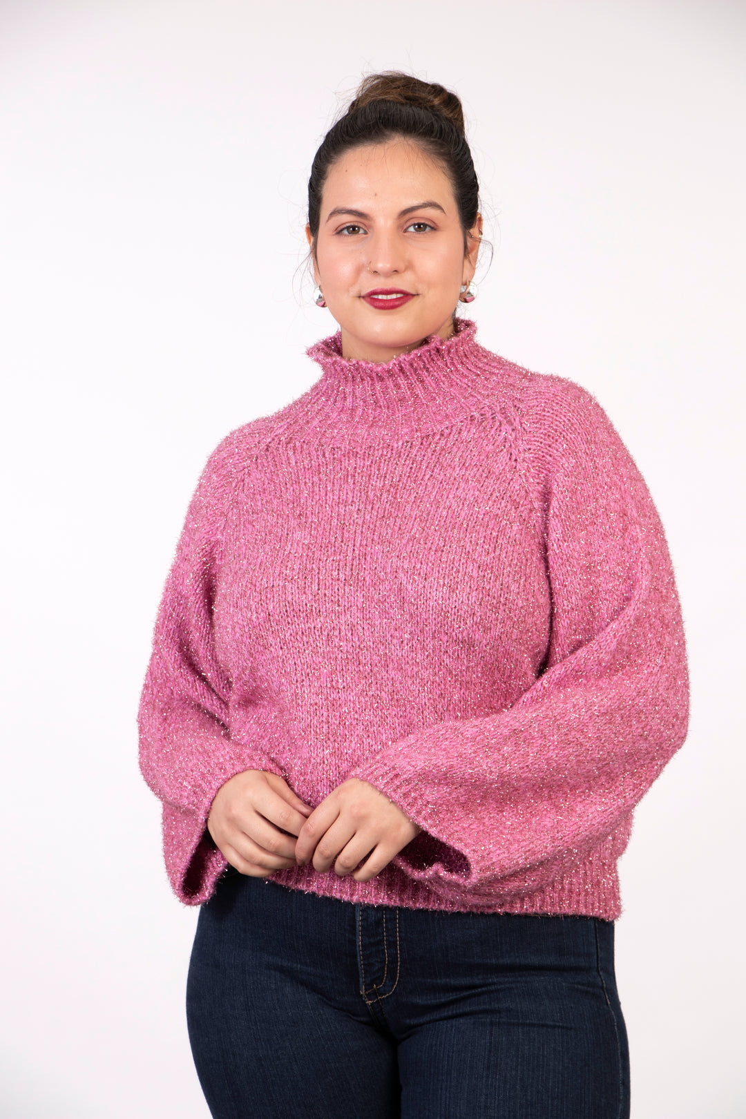 model wearing a pink sparkly knitted jumper, with a knitted high neck and an all over sparkly silver tinsel effect.