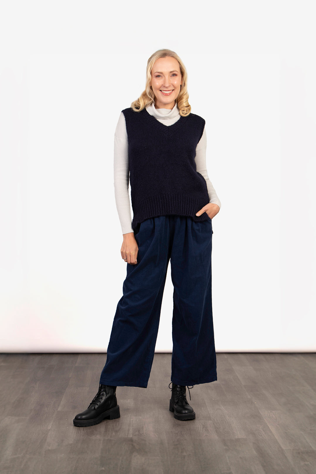 model wearing a navy blue sleeveless knitted tank top with a v neck and ribbed texture