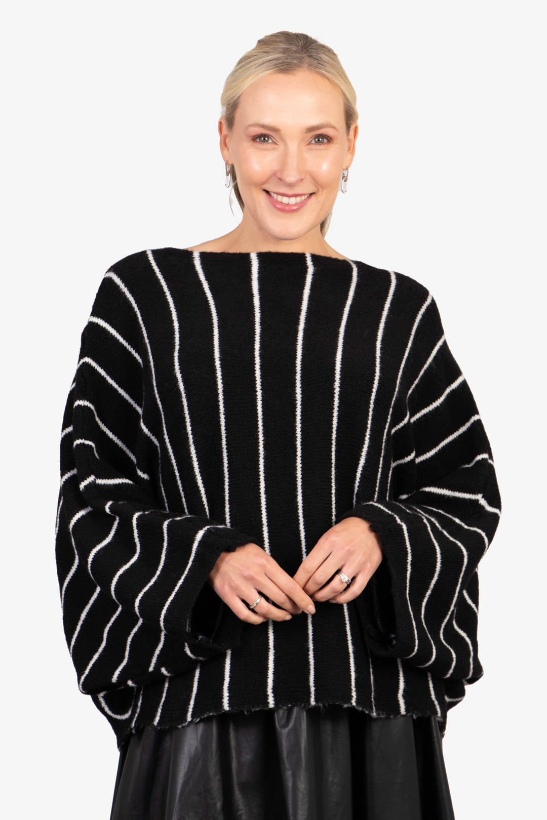 model wearing an oversized black knitted jumper with vertical white stripes and a boat neck