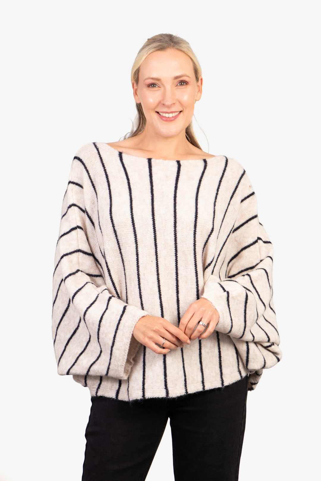 model wearing an oversized cream knitted jumper with vertical black stripes and a boat neck