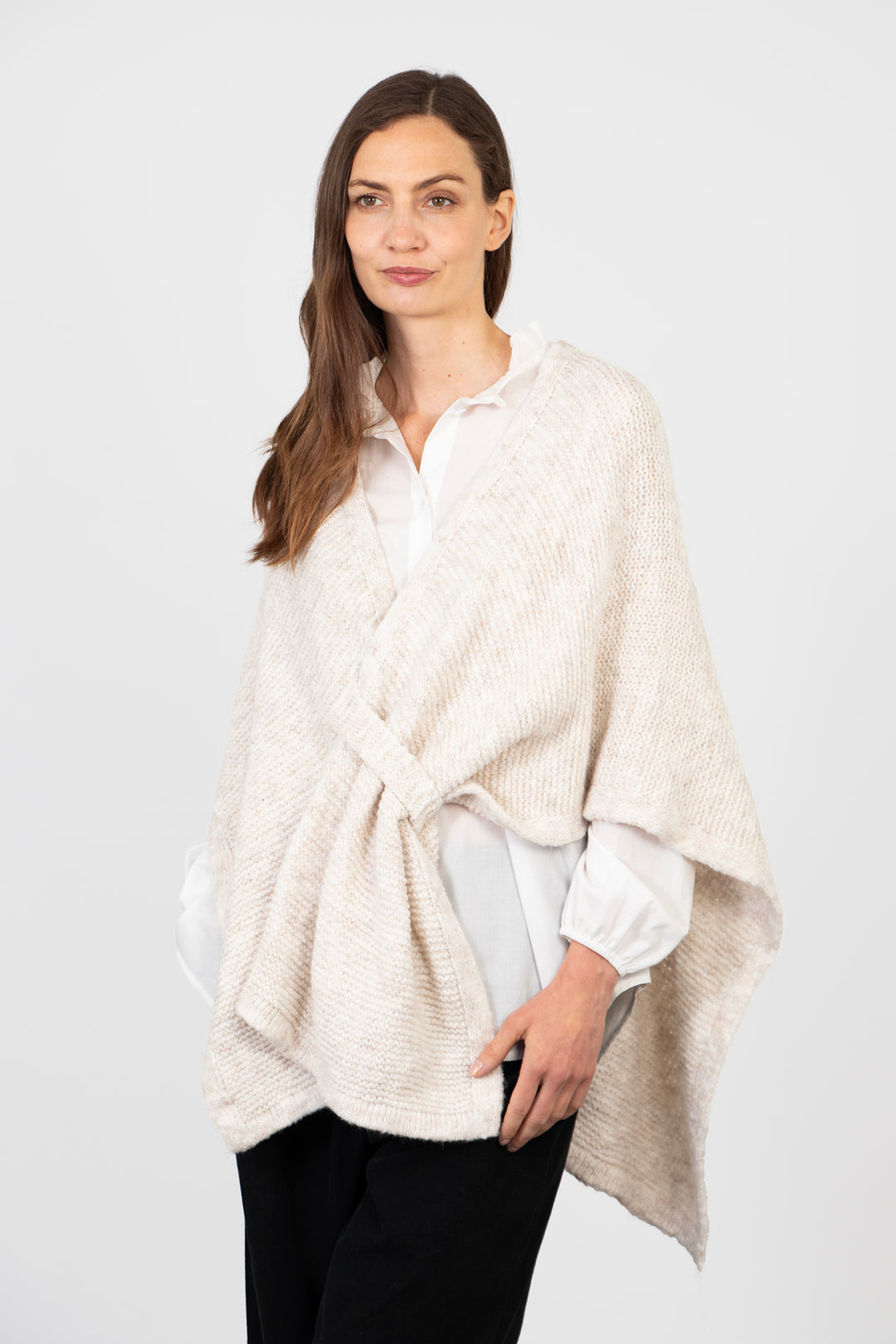 model wearing a cream knitted tuck through wrap with an asymmetric hem