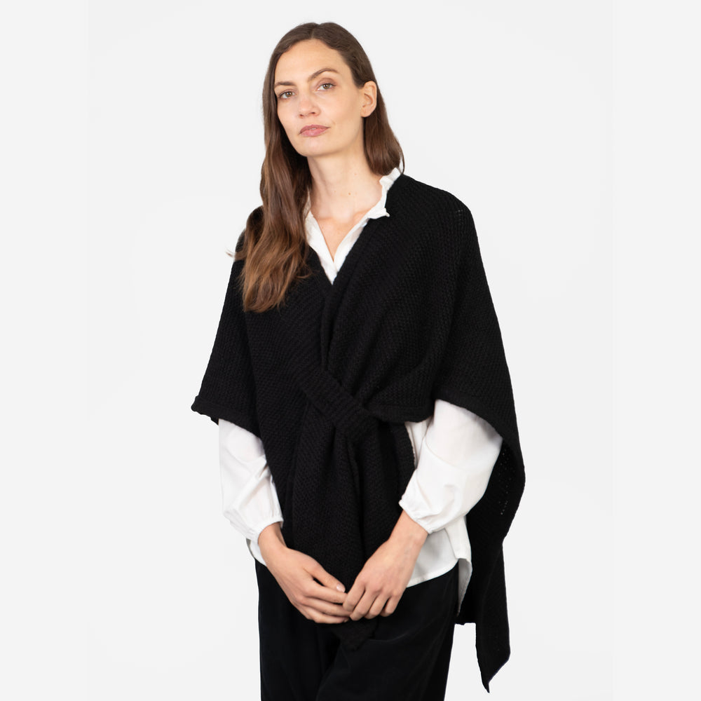 model wearing a black knitted tuck through wrap with an asymmetric hem and v-neck