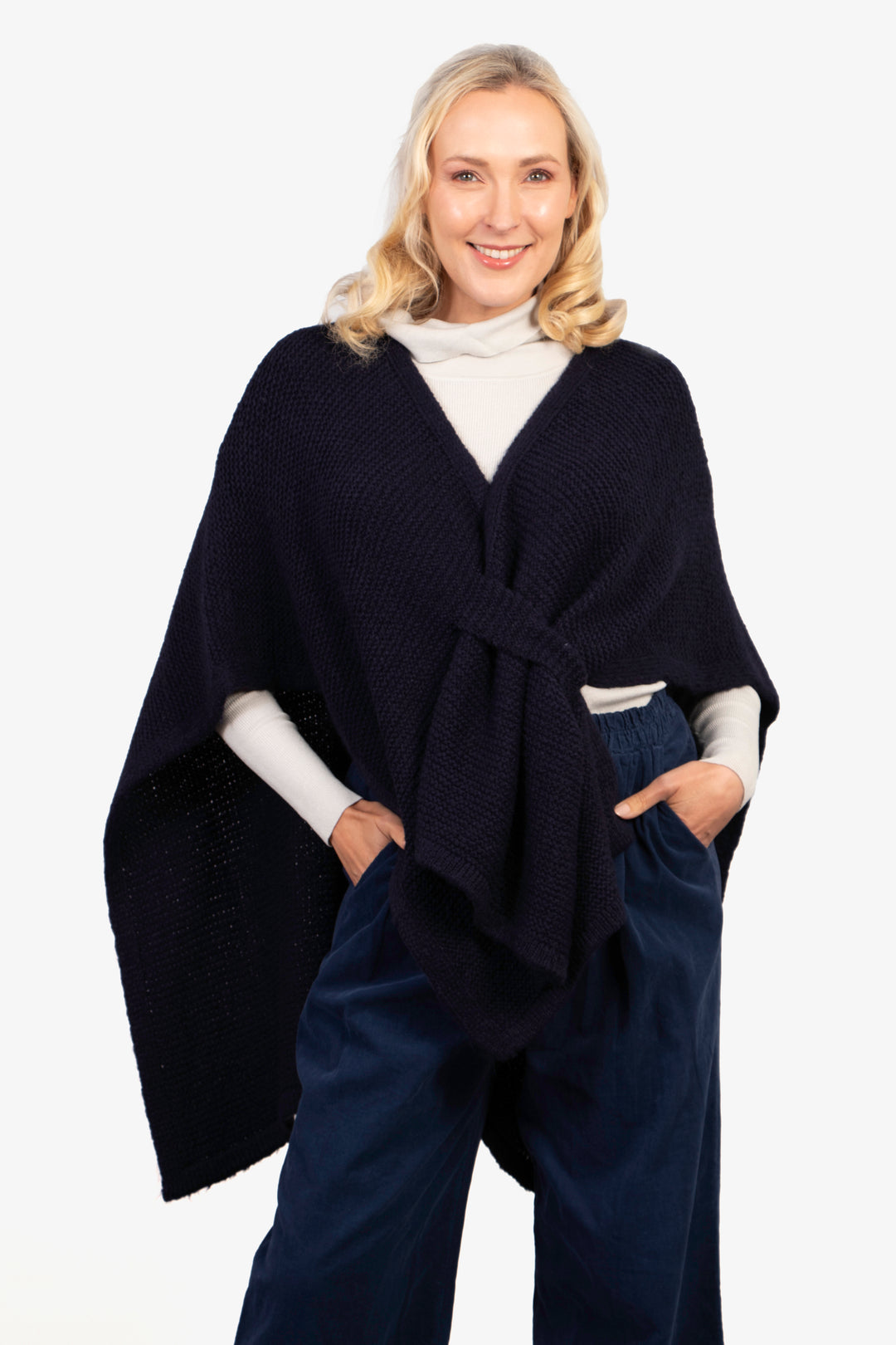 model wearing a plain navy blue knitted tuck through sleeveless wrap poncho