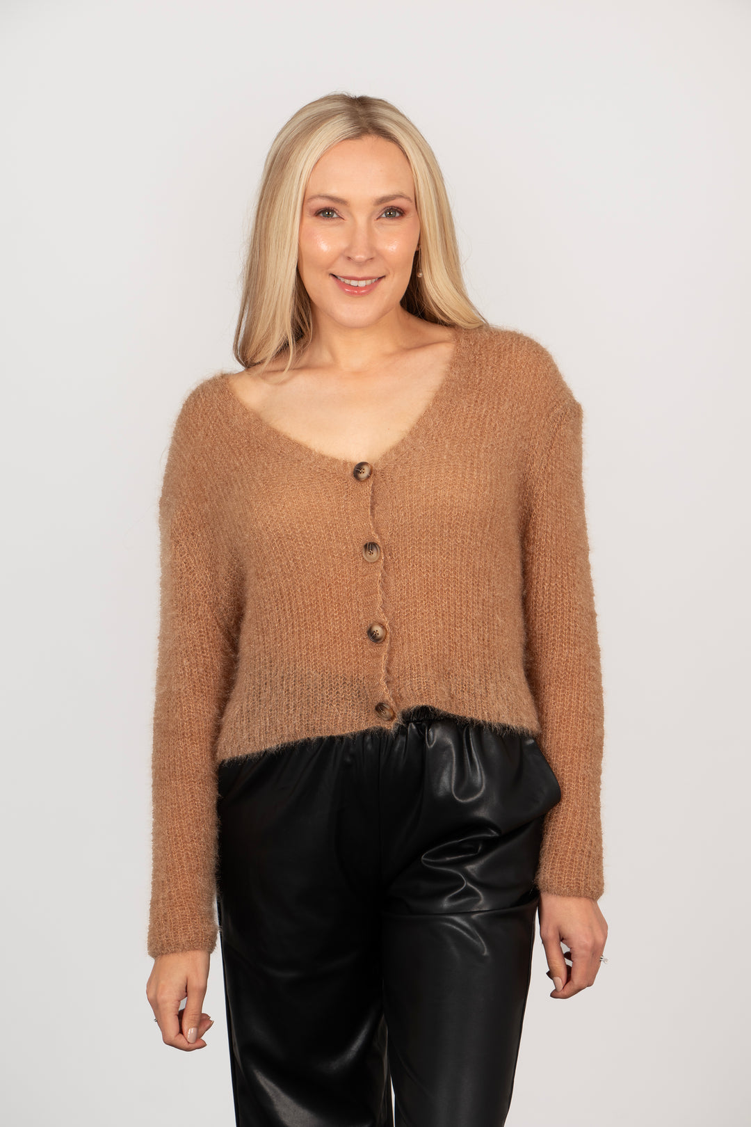 model wearing a neutral tan coloured button front cropped cardigan with long sleeves and a v-neck