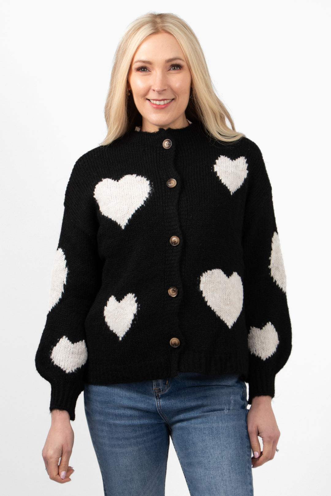 model wearing a black button up cardigan with a pattern of large cream love hearts all over the design. 