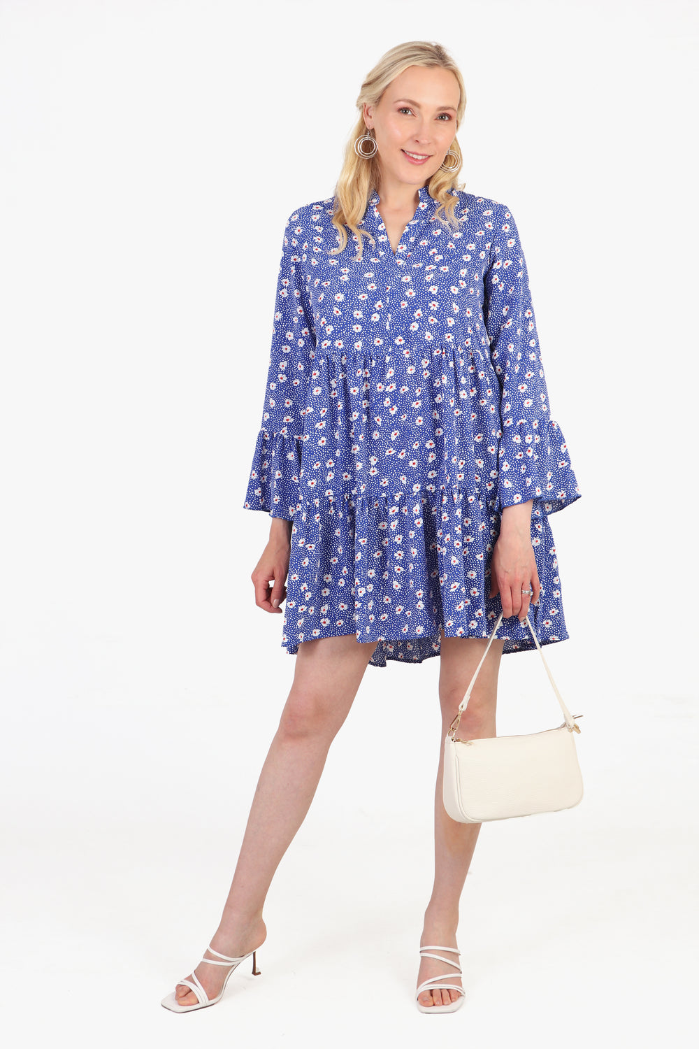 short blue daisy floral mini dress being worn by a model, the model is wearing prominent hoop earrings, sandals and a leather bag showing how this dress can be styled for an occasion