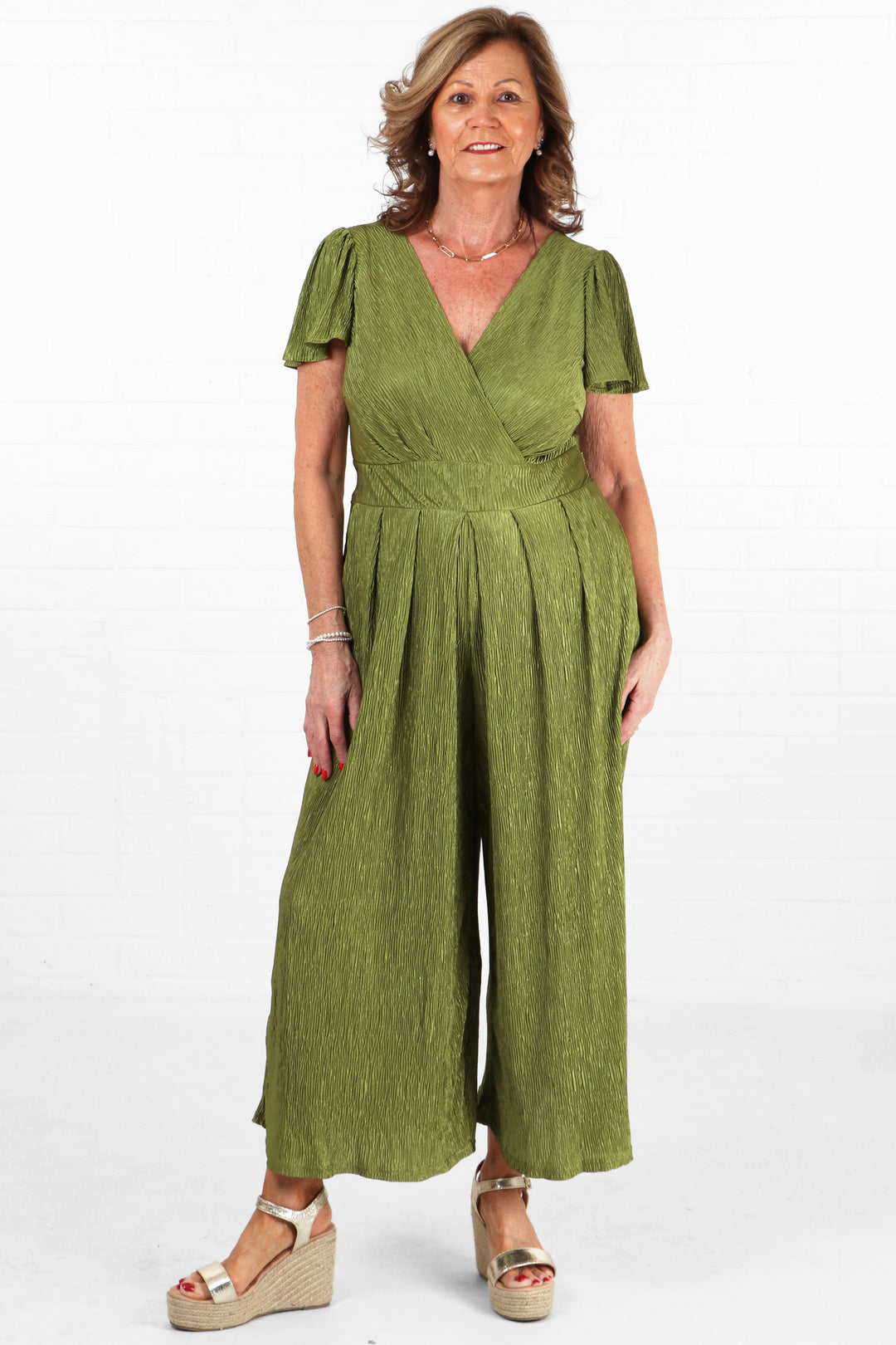 model wearing an olive green plisse fabric jumpsuit with v neck and short angel sleeves