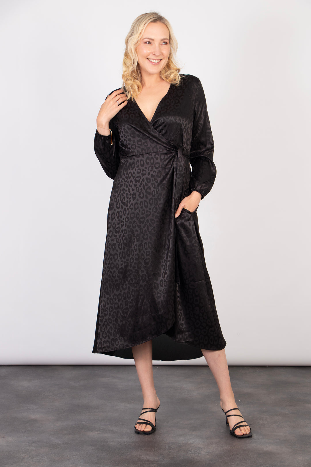 model showing that the black leopard print wrap dress has pockets on the side