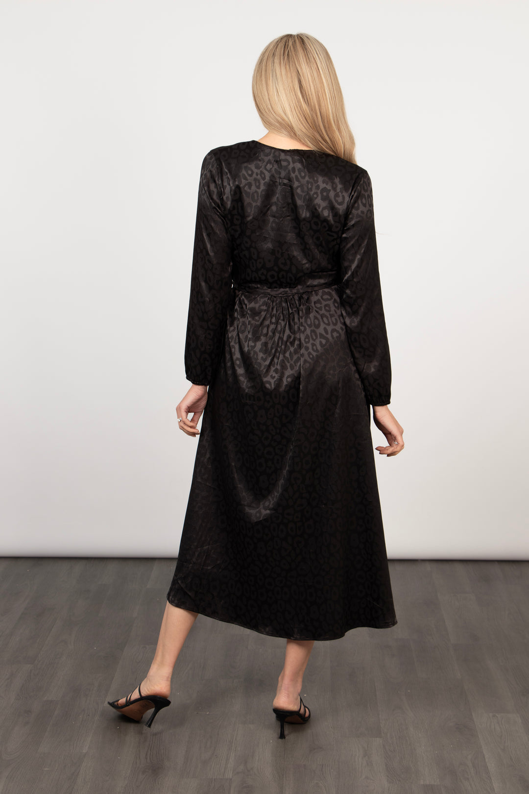 model showing the back of the black leopard wrap dress, the hemline is midi length and the dress has a waist tie fastening