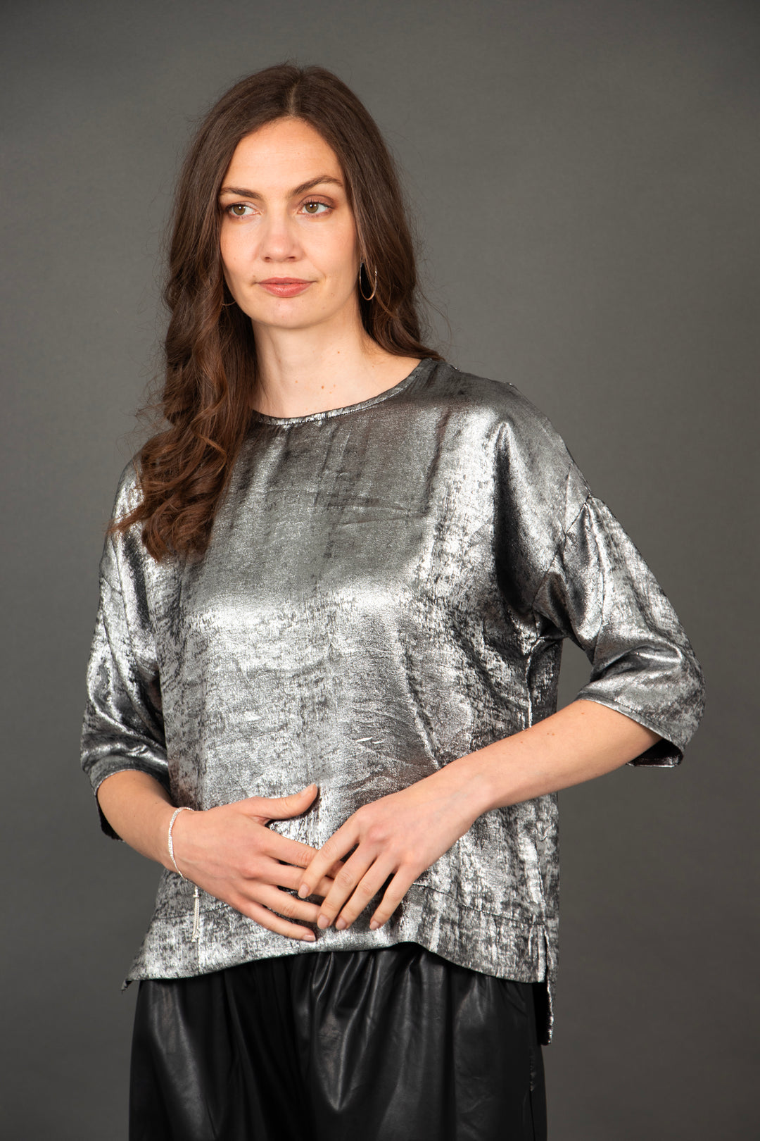 model wearing a silver metallic cropped sleeve box top with a dipped hem and round neck