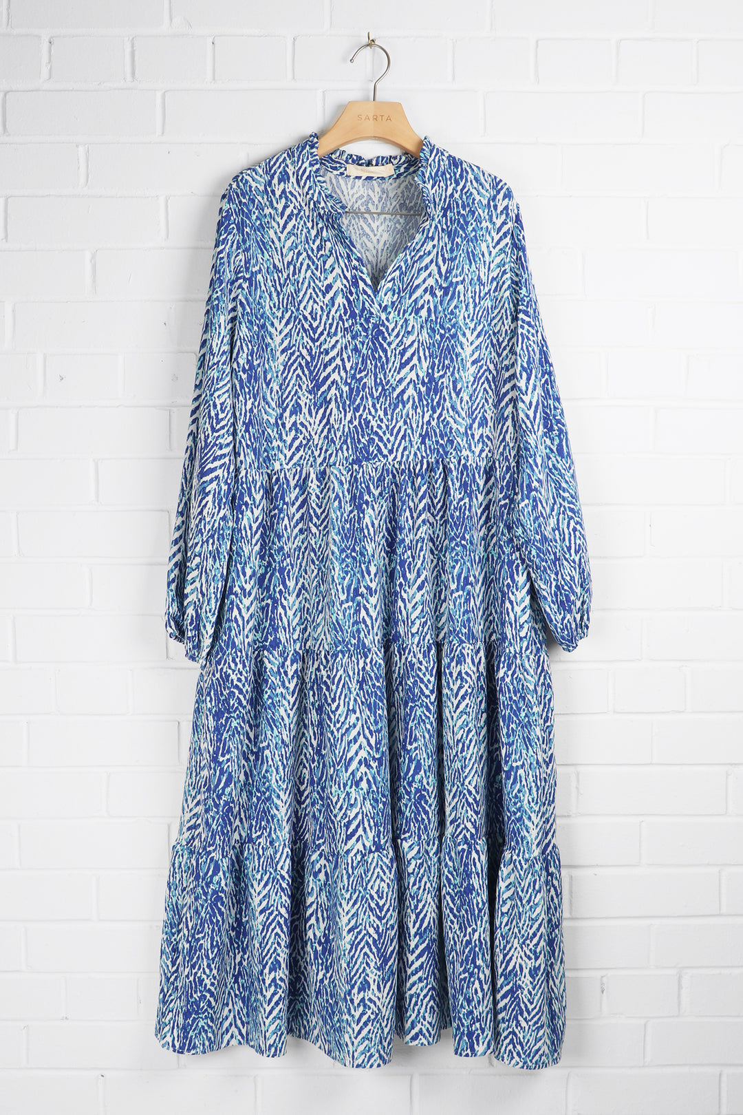 blue chevron print midi dress with long sleeves draped on a coat hanger