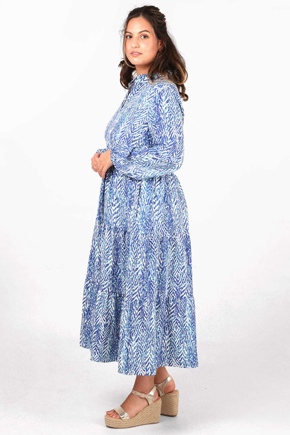 mode showing the side of the dress, showcasing the long sleeves and tiered skirt of the dress