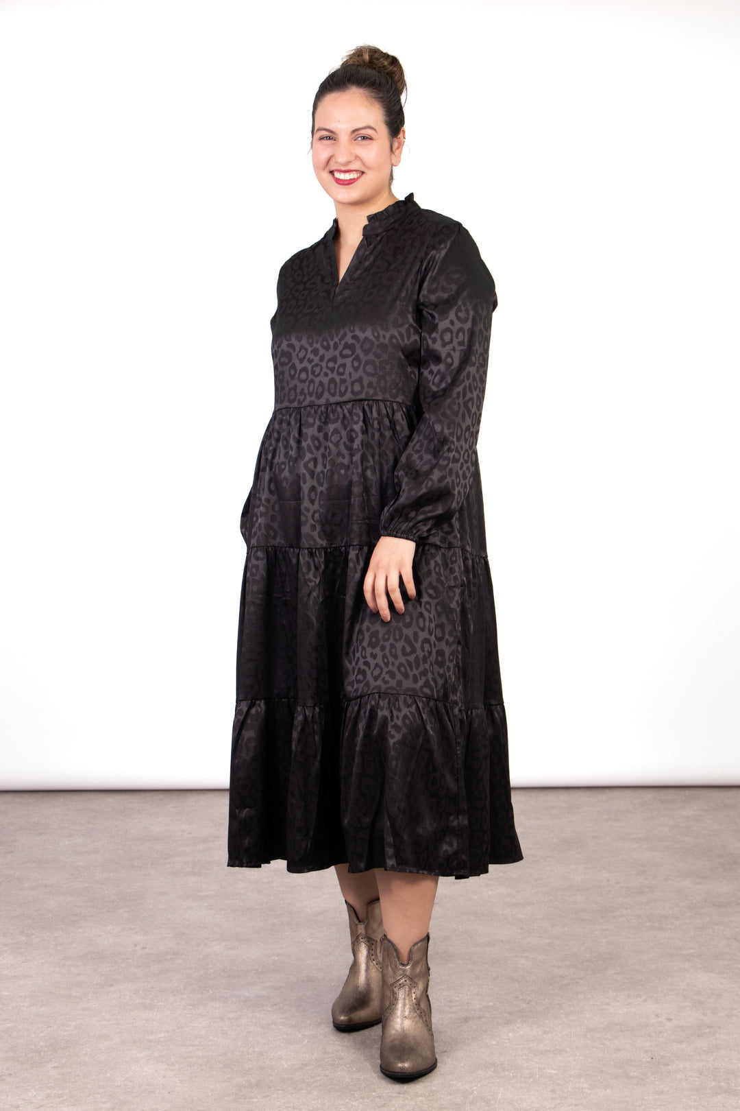 model wearing a black leopard print tiered midi dress, the dress has an open v-neck and long sleeves