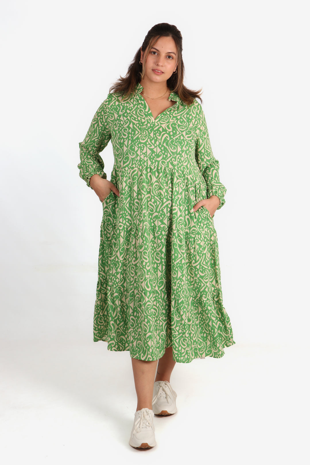 model wearing a midi length long sleeve dress with an all over aztec print pattern in green and cream