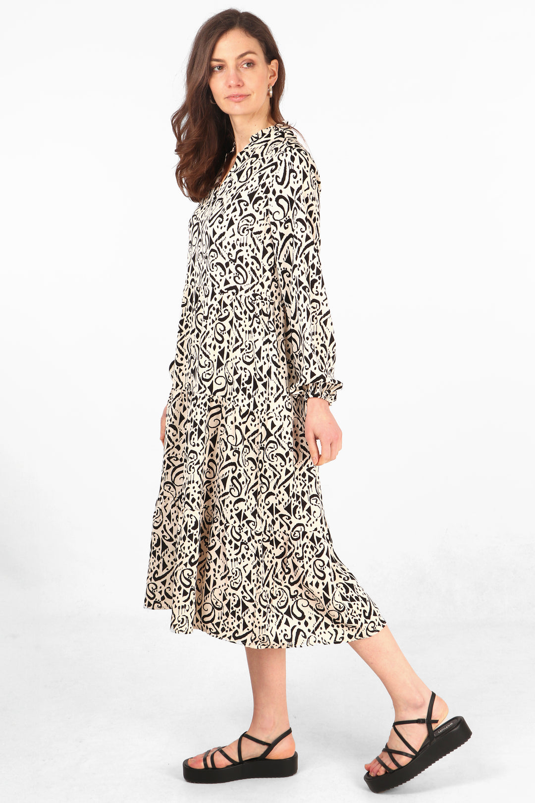 model wearing a cream and black aztec pattern tiered long sleeve midi dress with grandad collar