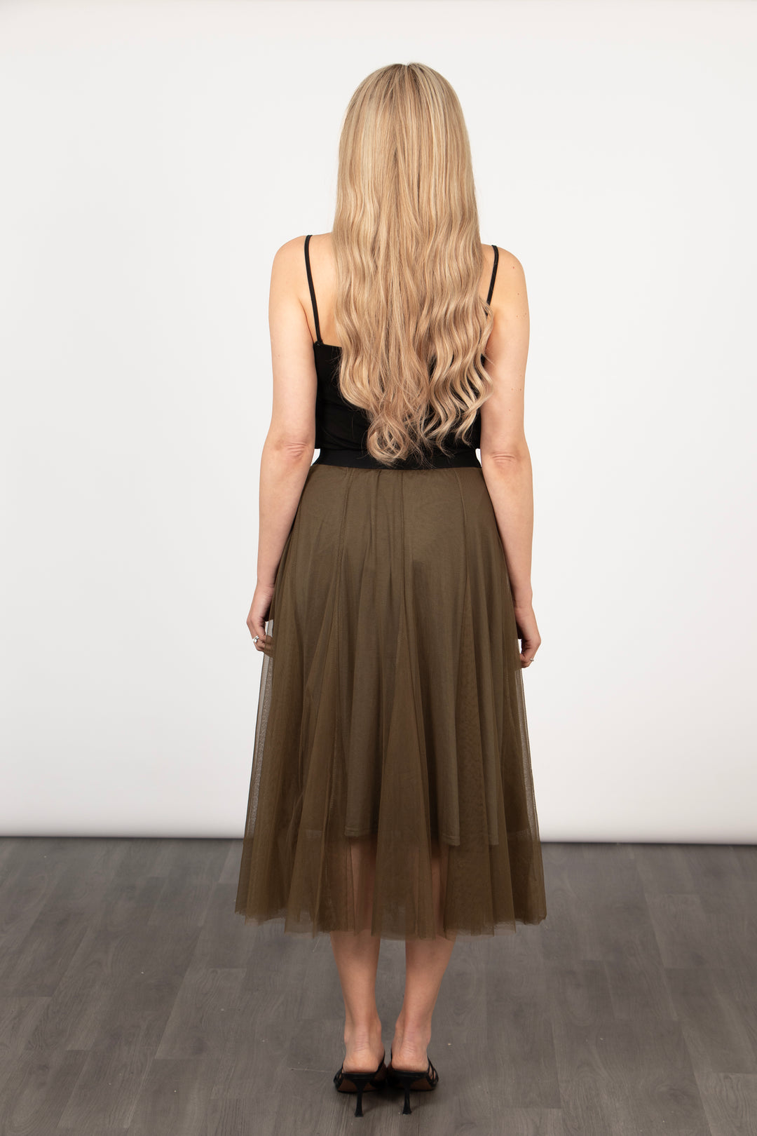 model showing the back of the khaki tulle skirt showing that the hemline falls midcalf