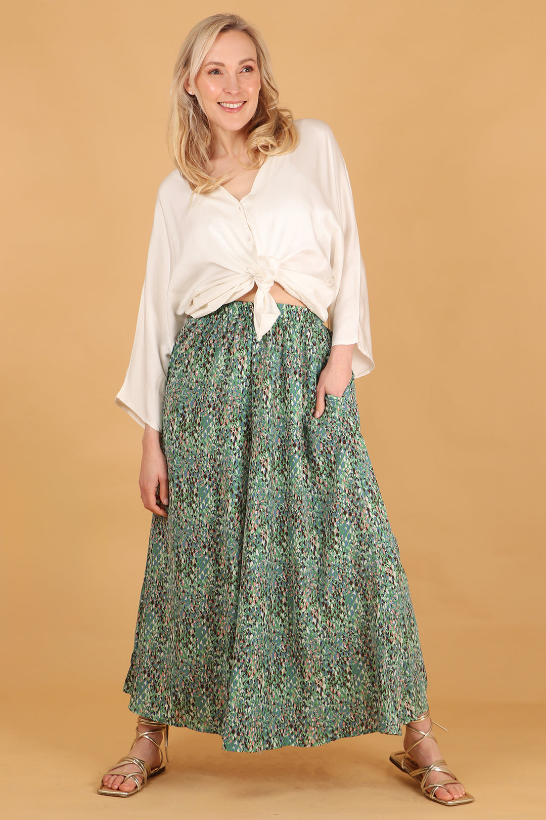 model wearing a pair of wide leg palazzo trousers with an all over abstract print pattern, the trousers have pockets