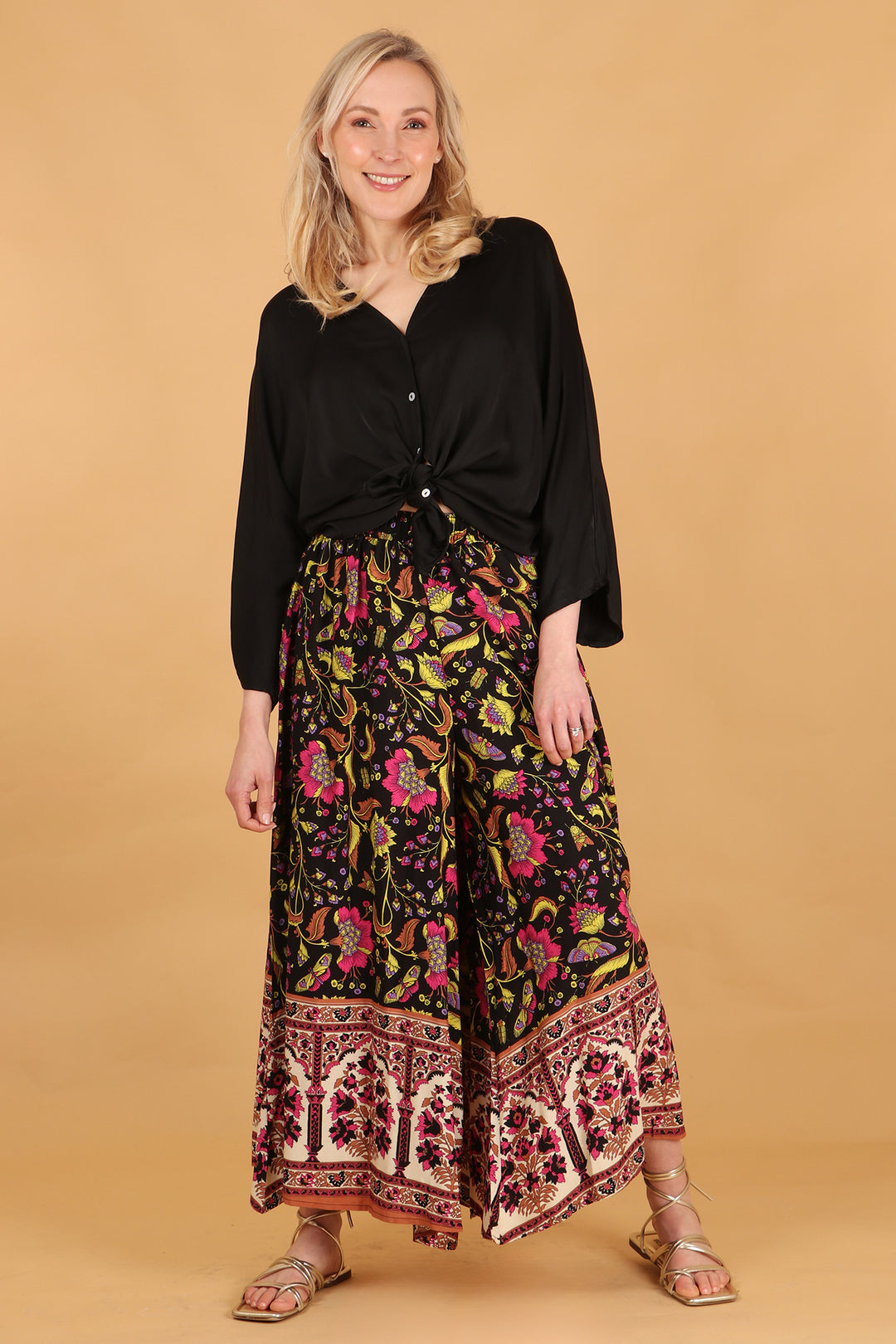 model wearing a paird of black, pink and yellow floral and butterfly patterned wide leg palazzo trousers
