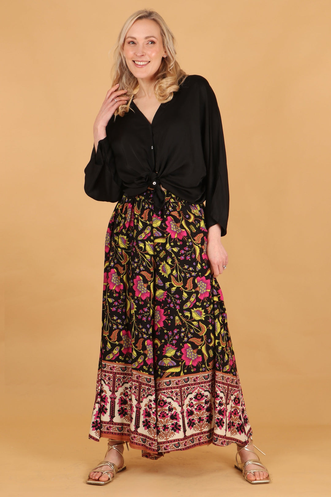model wearing a pair of loose fitting lightweight palazzo trousers with a vintage floral and buterfly pattern in black,pink and yellow
