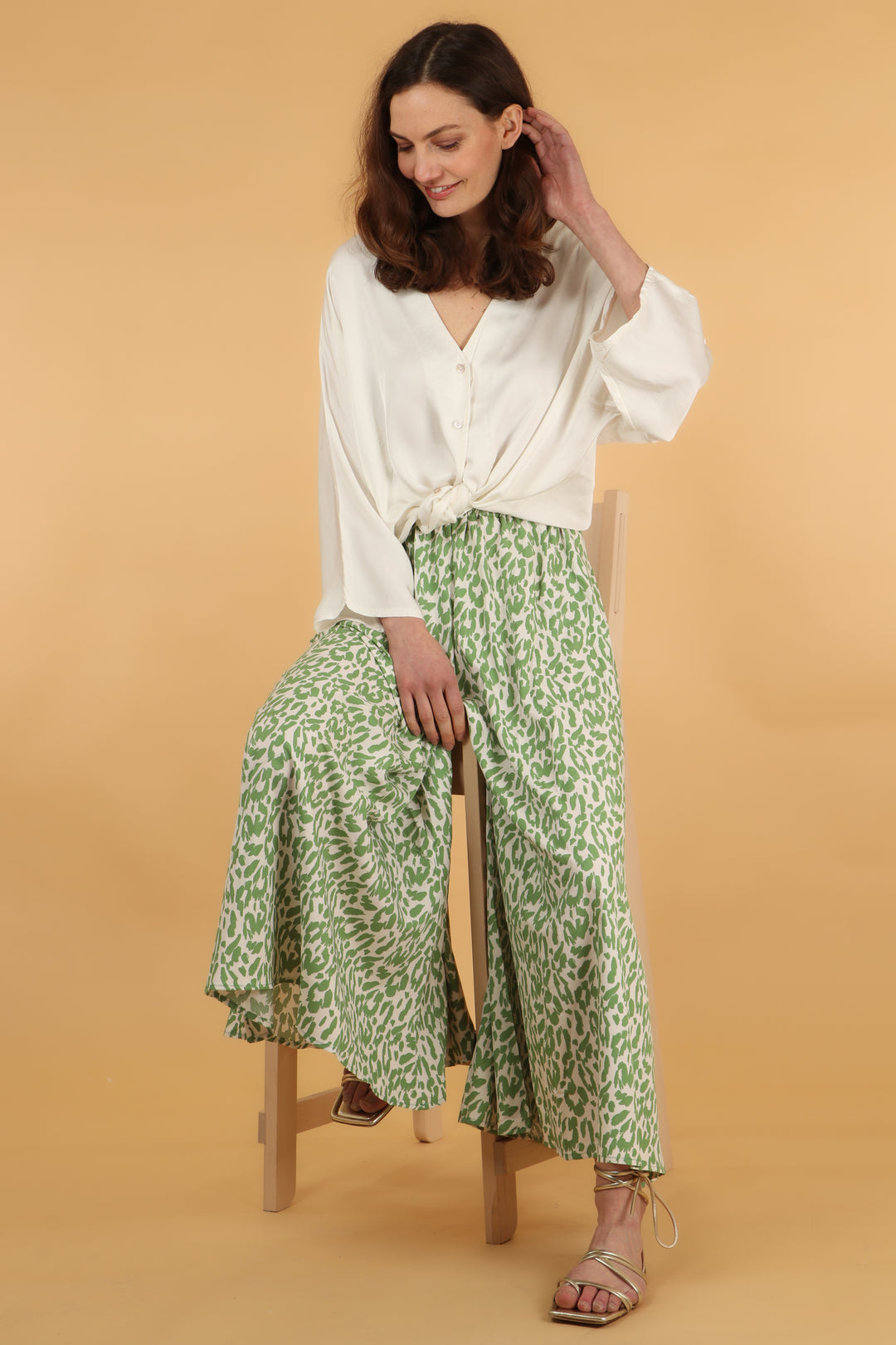 model wearing a pair of olive green large leaoprd print  palazzo trousers