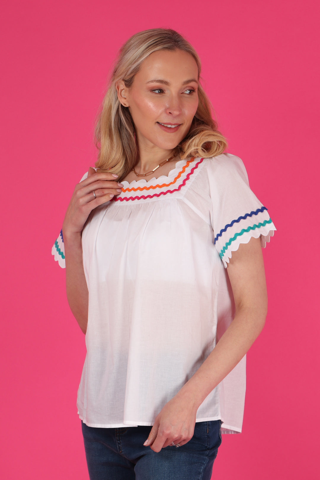 model wearing a short sleeve cotton blouse with colourful wavy trims on the sleeve and  around the neck line